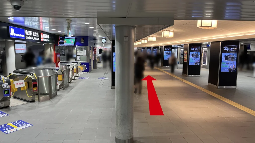 Alt:Signatureグラングリーンゲートタワーへのアクセス方法:Osaka Metro御堂筋線梅田駅の北改札外通路で、左側にシルバーの自動改札機が並び、右側にデジタルサイネージの柱が連続して立っている様子。