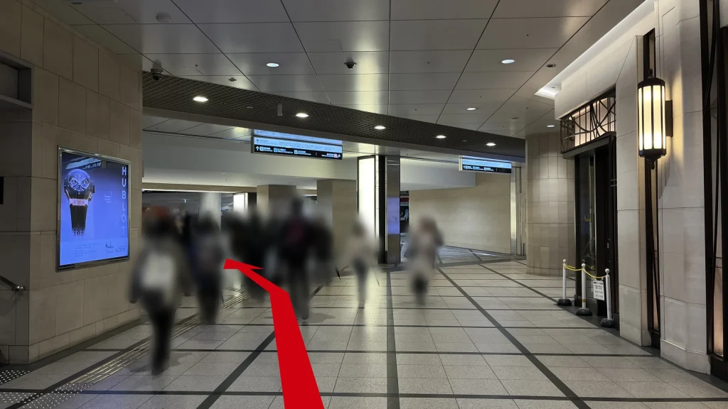 Signature大阪梅田ツインタワーズ・サウスへのアクセス方法：右側に阪急百貨店の入り口が続く地下通路。左側には広告が設置された壁とその左側には上に伸びる出口に向かう階段がある