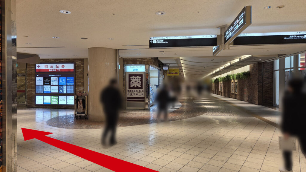 ZXY梅田への行き方：ディアモール大阪の通路の写真　左奥に「←岡三証券」と書かれた看板とビルのテナント一覧と左に伸びる通路、その奥通路側にドラッグストアと縦に伸びる通路がある