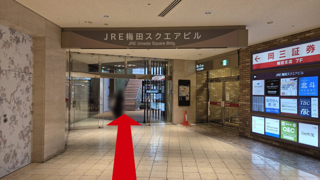 ZXY梅田への行き方：「JRE梅田スクエアビル」の地下連絡通路　右に「岡三証券」のテナント看板と外へつながる「E-2」出口が見える