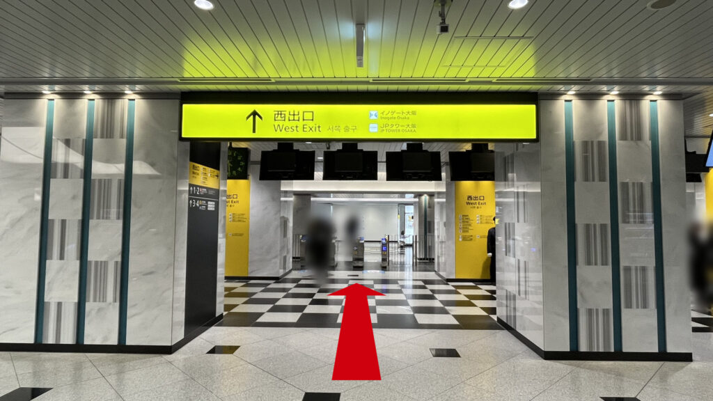 SYNTH×Business-Airport 西梅田ブリーゼタワーへのアクセス方法：JR大阪駅西口改札（西出口）に向かっている様子　上にある黄色い大きな看板には「↑西出口」「イノゲート大阪」「JPタワー大阪」と書かれている