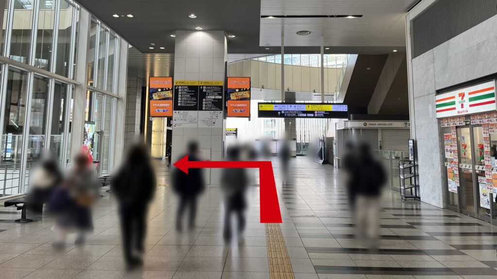Compass Offices イノゲート大阪へのアクセス:右手にセブンイレブン、左手にガラス張りの窓がある 正面には大きな柱に案内掲示が貼られており、正面右にはインフォメーション、正面奥には案内板が吊り下げられている