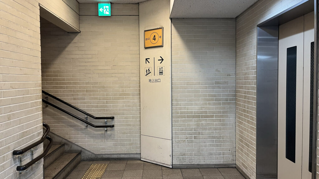 BIZcomfort大阪東梅田へのアクセス方法:地下から地上へ続く「4番出口」の階段とエレベーターのピクトグラム案内 右手にエレベーター、左手に上へ上る階段