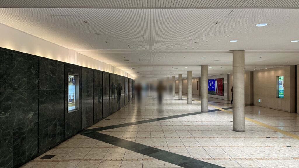 SYNTH×Business-Airport 西梅田ブリーゼタワーへのアクセス方法：等間隔に白い円柱が配置された地下通路　左手に大理石のような石の壁が連なっている