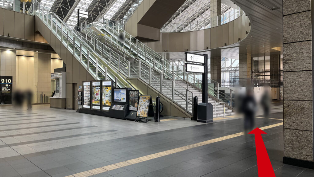 SHARE LOUNGE梅田 蔦屋書店へのアクセス方法：エスカレーターで3Fまで上がって右を向いたときの風景　中央にエスカレーターと階段があり、右手に大きな柱と大阪駅改札への道、階段下に案内板や広告が置かれており、その左手にインフォメーションカウンターが見える
