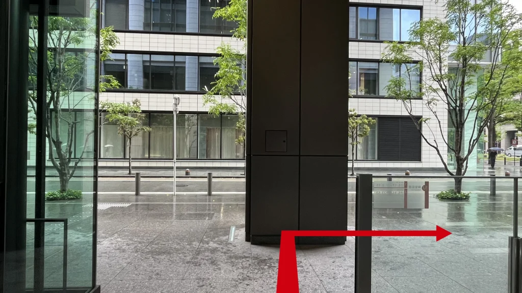 リージャス淀屋橋ビジネスセンターへのアクセス方法：地上出口から外に出た直後の景色。正面にグレーのビルが見え、足元はタイル貼りになっている。