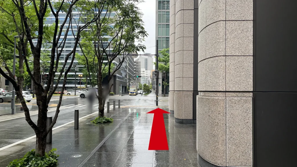 リージャス淀屋橋ビジネスセンターへのアクセス方法：ビルの太い円柱が並ぶ歩道を、御堂筋の交差点方向へ進む様子。
