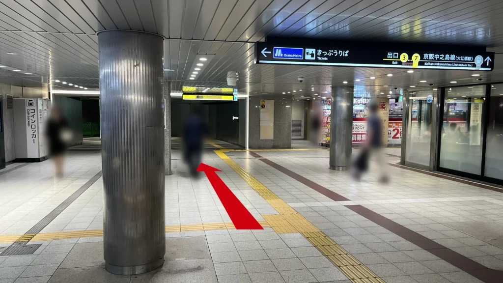 Signature大阪ダイビル本館へのアクセス方法：円柱が並ぶ通路の図　前方には「出口3」の黄色い案内看板が見えます。右斜前方にはドラッグストアが見えます。