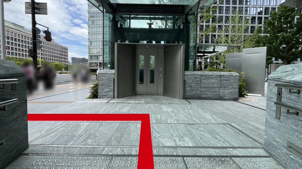 Signature大阪ダイビル本館へのアクセス方法：石造りの出口から地上に出た場所の写真　正面にはガラス張りのエレベーターシリンダーがあります。左手には大阪市役所が見えます