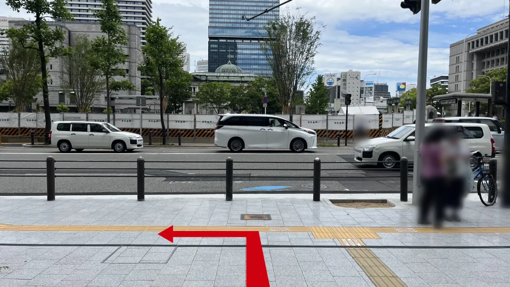 Signature大阪ダイビル本館へのアクセス方法：車道沿いの歩道の写真。奥の車道には白い乗用車が走っています。