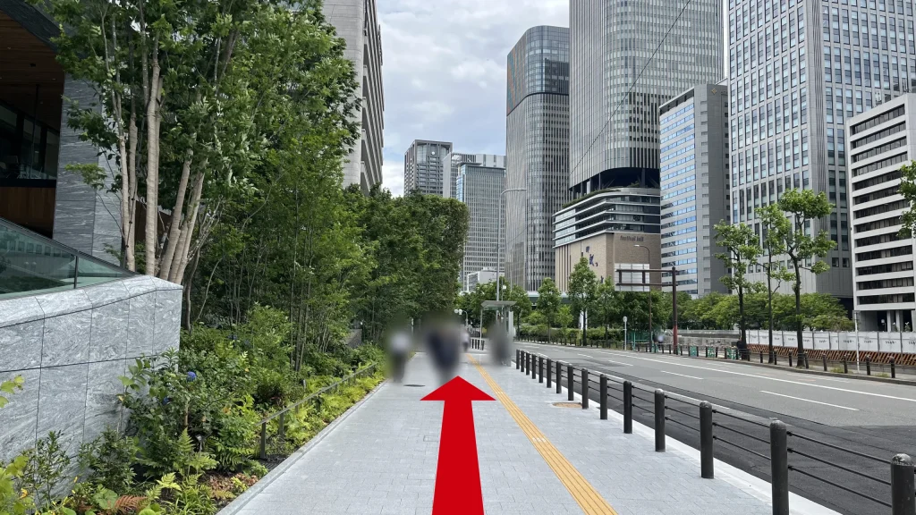 Signature大阪ダイビル本館へのアクセス方法：左側に植栽と石造りのビルがある広い歩道。前方には高層ビル群が見えます。