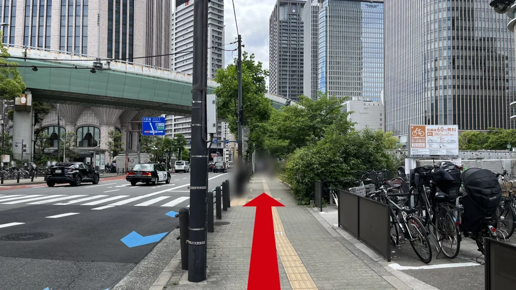 Signature大阪ダイビル本館へのアクセス方法：右側に多数の自転車が停まった駐輪スペースがある歩道。左側は車道です。