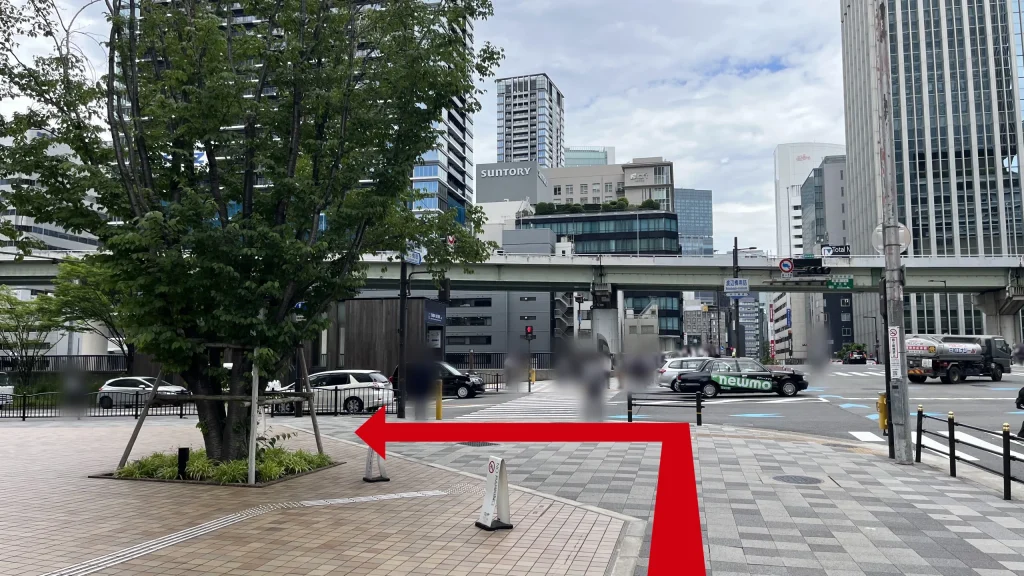 Signature大阪ダイビル本館へのアクセス方法：タイル敷きの広場の写真。左手には香雪美術館前の大きな植木、奥にはサントリーの看板があるビルが見えます。