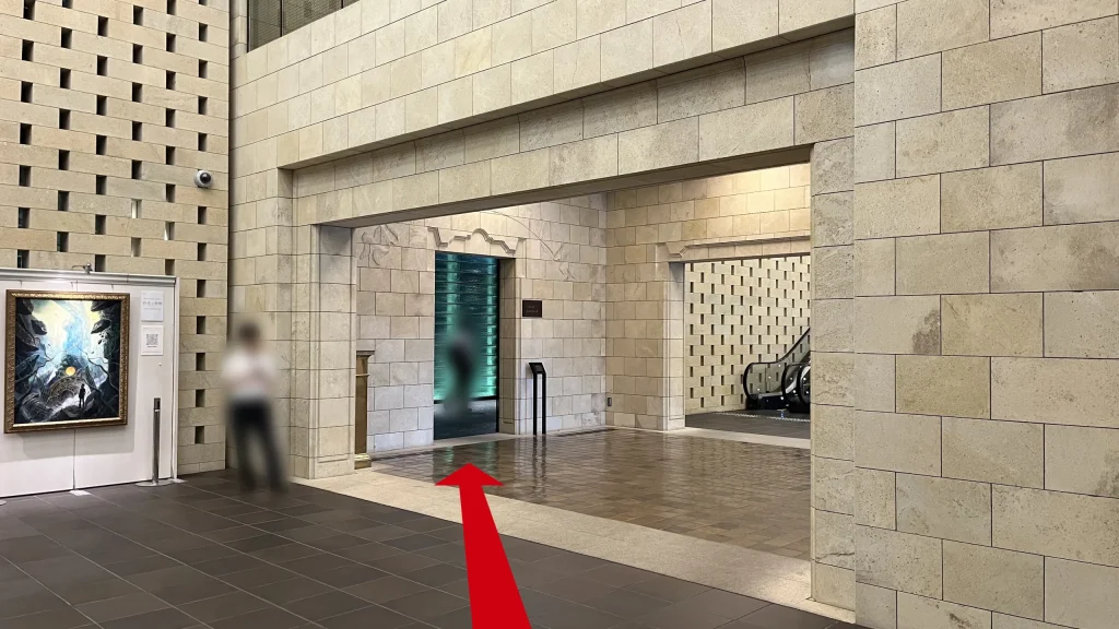 Signature大阪ダイビル本館へのアクセス方法：ベージュの石壁で囲まれた綺麗な館内通路の写真　前方にオフィスエントランス、右奥にエスカレーターが見える