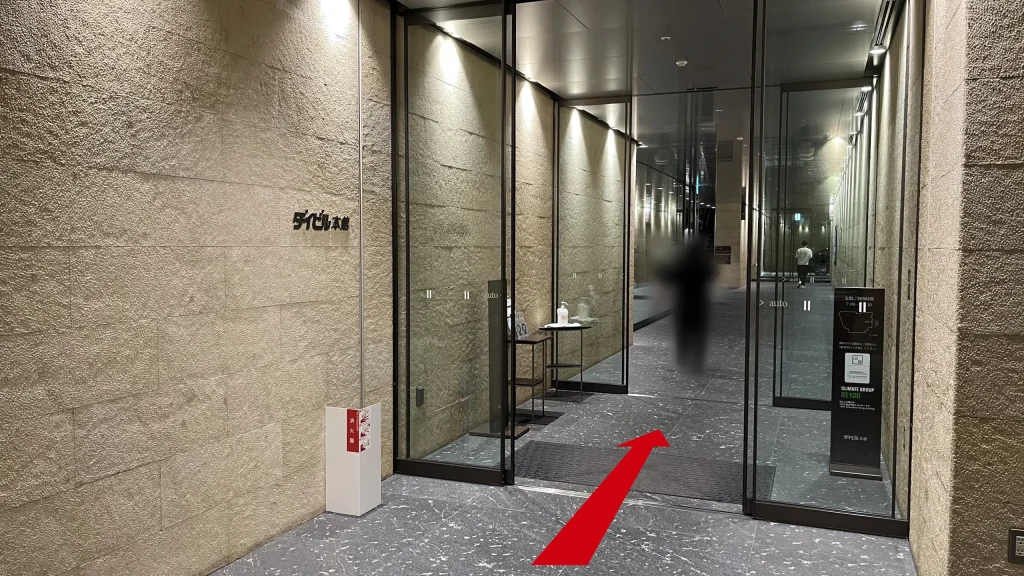 Signature大阪ダイビル本館へのアクセス方法：左側の石壁にダイビル本館と黒い文字で立体的に書かれた、ガラス張りの館内への自動扉エントランスが写っています。