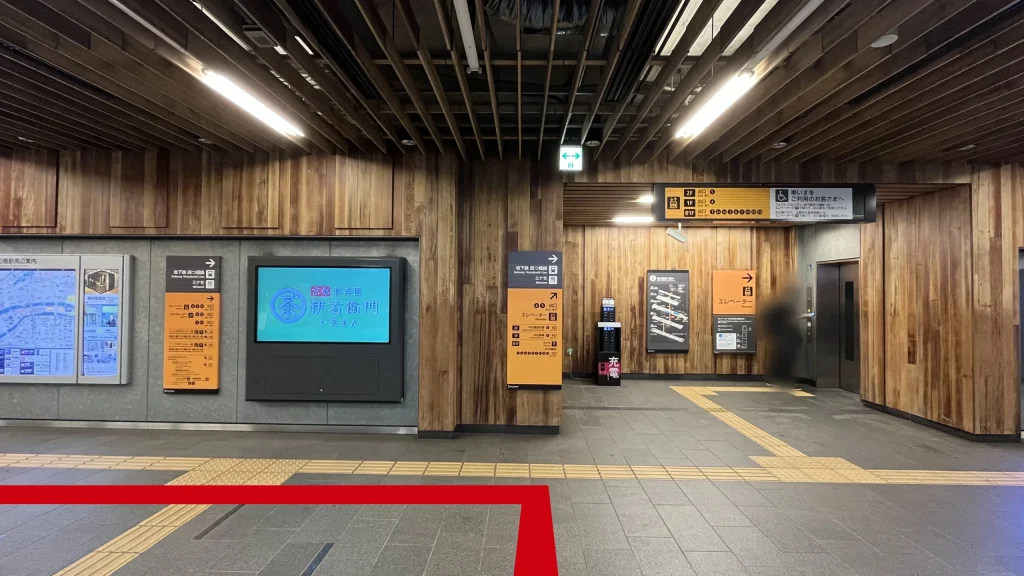 Signature大阪ダイビル本館へのアクセス方法：木目調の天井と壁で統一された京阪中之島線渡辺橋駅のコンコース　正面にエレベーター、左右に階段があるという案内板が掲示されている