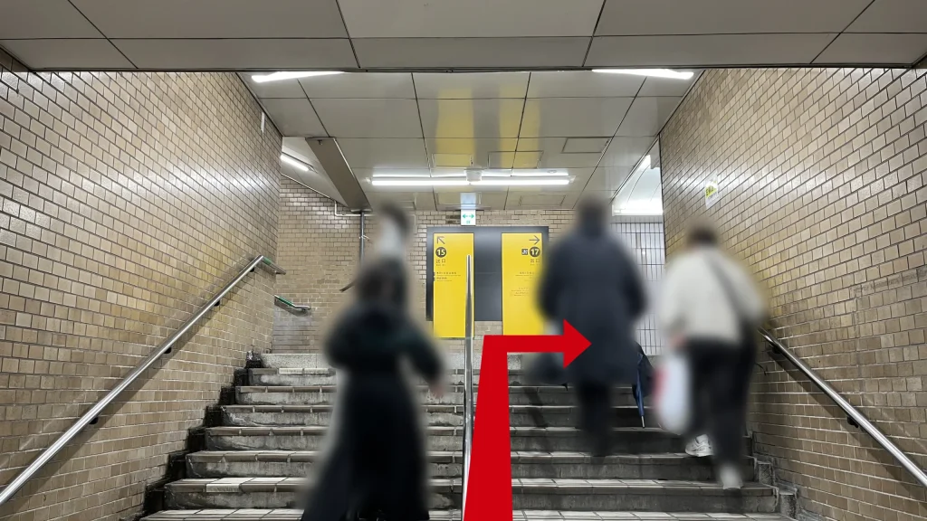 リージャス大阪国際ビルディングビジネスセンターへのアクセス方法：地下駅構内の茶色いタイル壁に挟まれた階段。正面奥の壁には「15 出口（左矢印）」と「17 出口（右矢印）」を示す黄色の案内板が設置されている。