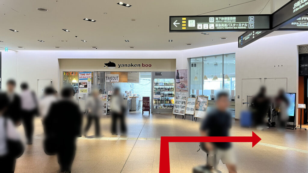リージャス新大阪阪急ビルビジネスセンターへの行き方：通路の突き当たりにある飲食店の外観と、頭上に設置された「地下鉄御堂筋線」や「高速バスターミナル」へ誘導する黒い案内看板。