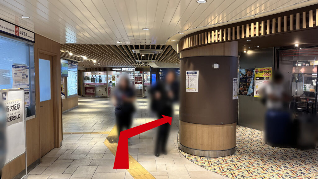 リージャス新大阪阪急ビルビジネスセンターへの行き方：Osaka Metro御堂筋線の北東改札口付近。通路の右側には円柱状の柱があり、周囲の壁面や天井は落ち着いた茶色ベースの木目調で統一されている。